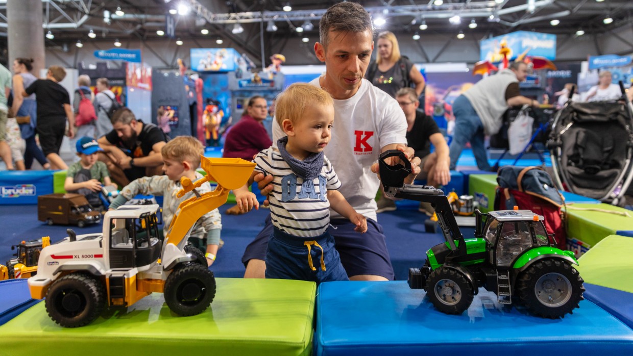 Ein Vater schaut sich mit seinem Kind 2 Spielzeug Bagger an.