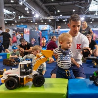 Ein Vater schaut sich mit seinem Kind 2 Spielzeug Bagger an.