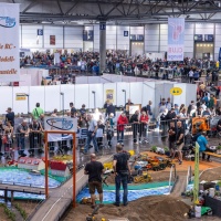 Eine große Ausstellung an ferngesteuerten LKWs. Eine große Anzahl an Besuchern ist zu sehe.