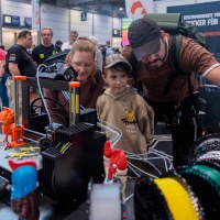 Eine Familie schaut sich ein Ergbenis eines 3D-Druckes an.
