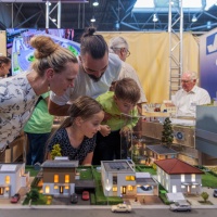 Eine Familie schaut sich einen Modellbau einer Wohnsiedlung an.