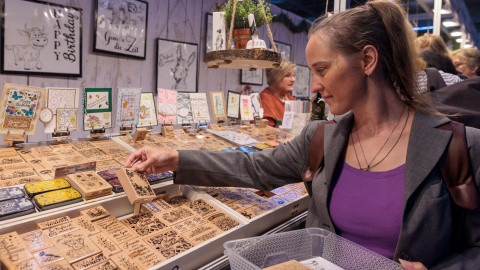 Eine Frau schaut sich das Sortiment eines Verkaufstandes an. Sie hält eine Holzschachtel in der Hand.