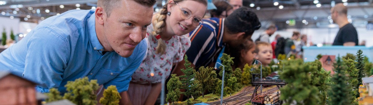 Eine Frau und ein Mann schauen sich eine Modellbaueisenbahn an.