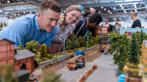 Eine Frau und ein Mann schauen sich eine Modellbaueisenbahn an.