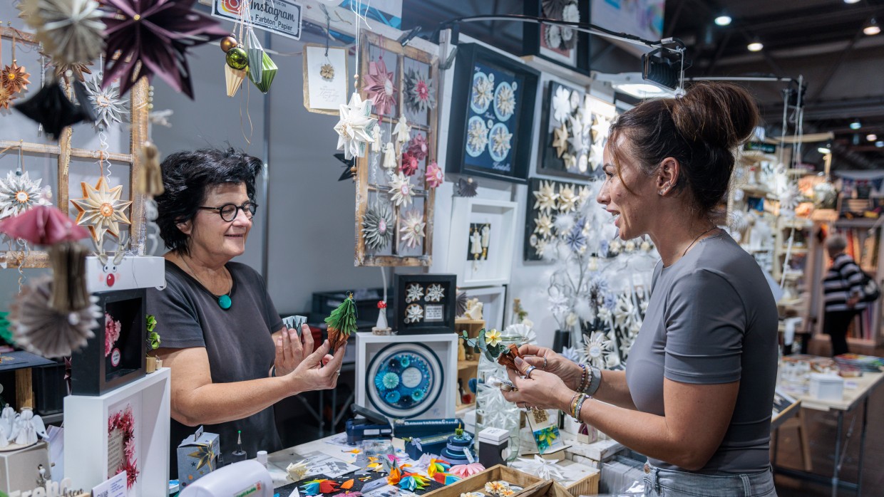 Eine Frau wird an einem Verkaufsstand von einer anderen Frau beraten.