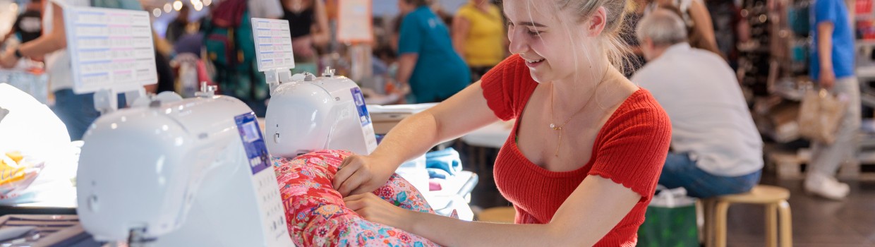 Eine Frau näht an einer Nähmaschine ein Nackenkissen.