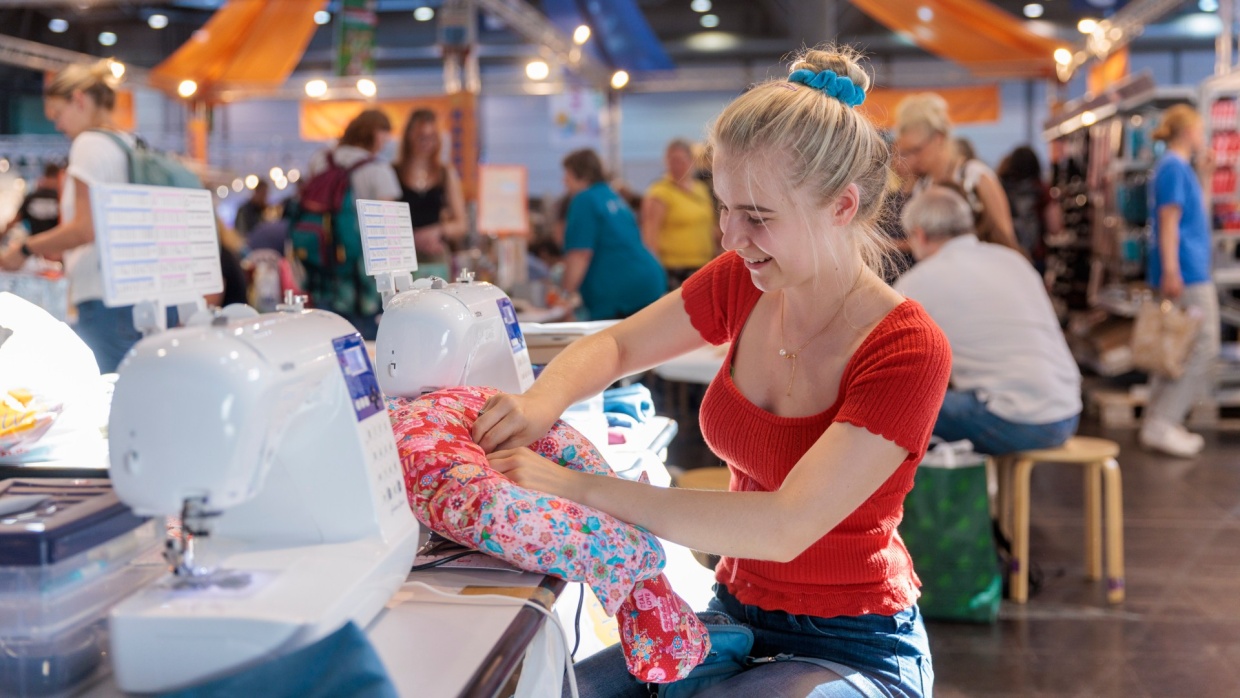 Eine Frau näht an einer Nähmaschine ein Nackenkissen.