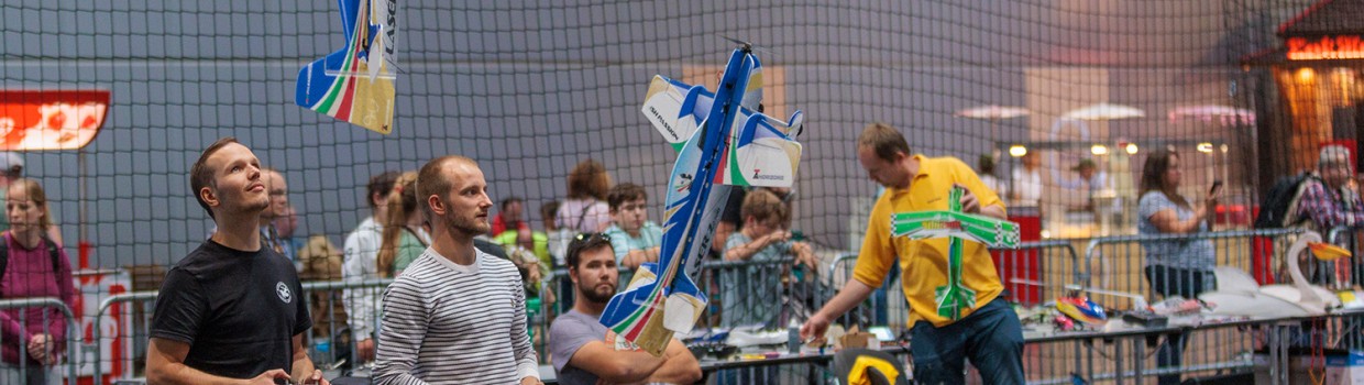 In der Halle werden Kunststücke mit Ferngesteuerten Flugzeugen gemacht.