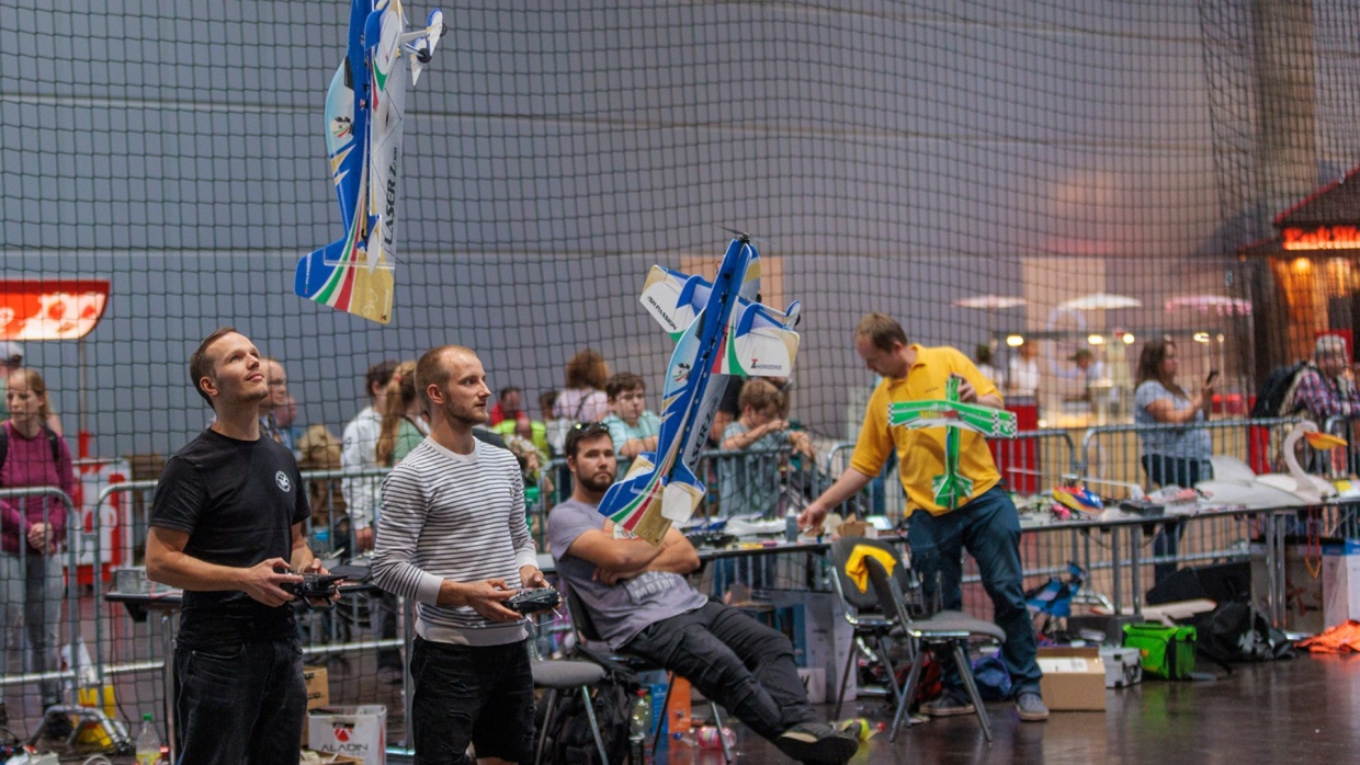 In der Halle werden Kunststücke mit Ferngesteuerten Flugzeugen gemacht.