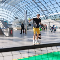 Ein Mann spielt in der Glashalle Tennis.