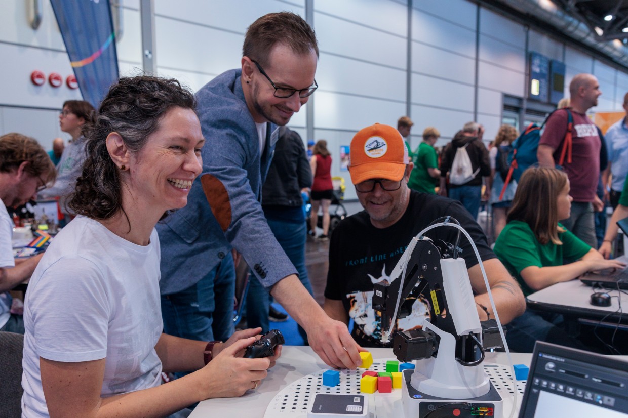 Einer Frau und einem Mann wird ein Roboterarm vorgestellt. Einer Frau und einem Mann wird ein Roboterarm vorgestellt.