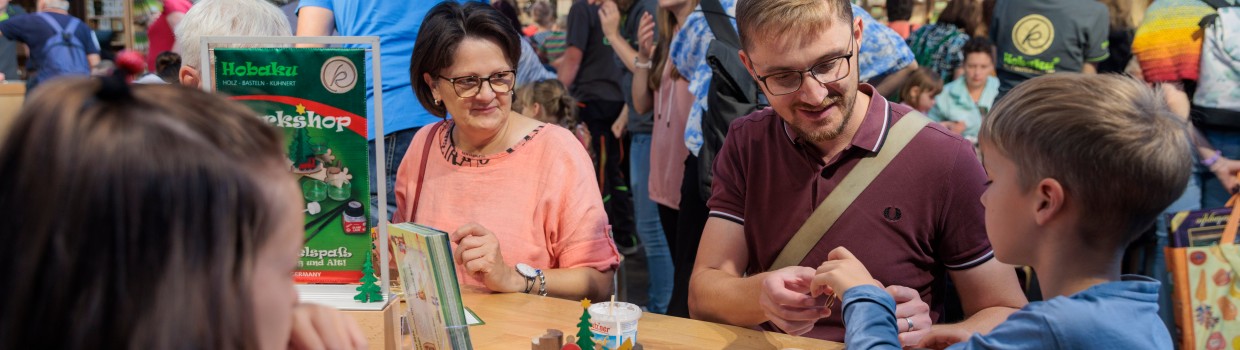 Eine Familie sitzt in einem Workshop und bastelt.