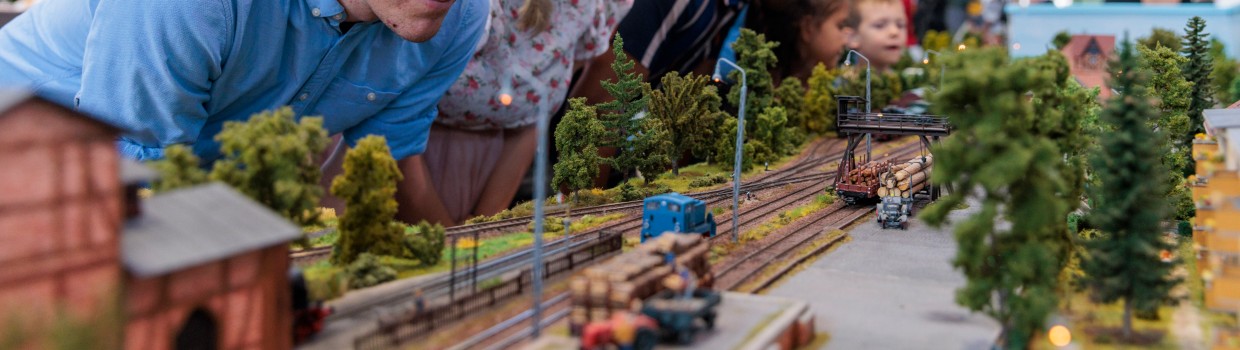 Eine Frau und ein Mann schauen sich eine Modellbaueisenbahn an.