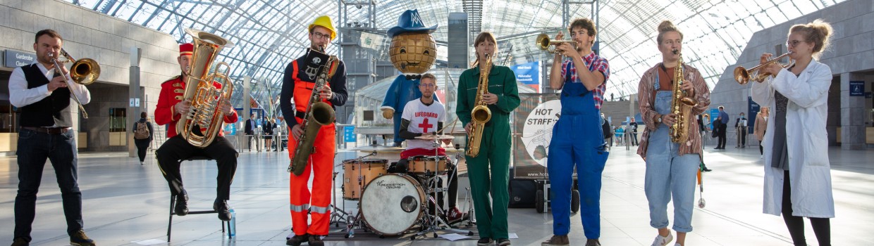 Viele unterschiedliche Personen die die Hobbymesse darstellen stehen in einer Reihe in der Glashalle.