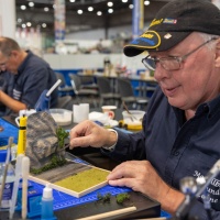 Ein Mann bastelt an einer Modell einer Felswand.